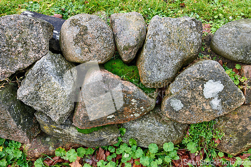 Image of Background. Nature background of a rock garden wall outside on a sunny day with delicate moss and plants growing between the stones. Wallpaper of structural support barrier fencing in a garden.