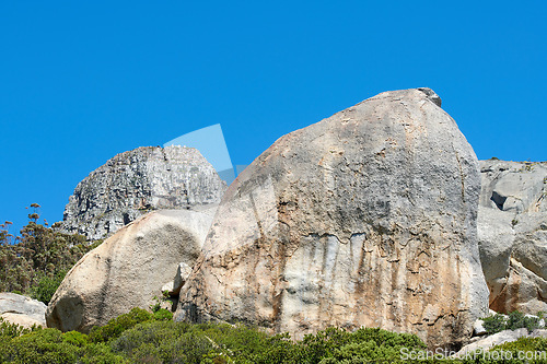 Image of Rocks and boulders on a mountain peak with green lush bush growing on Lions Head in Cape Town with sky and copyspace. Large area of wilderness landscape with calm fresh air and harmony in nature