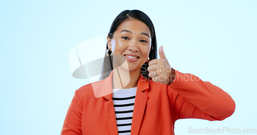 Image of Portrait, smile and thumbs up with a business asian woman in studio on a blue background or support. Thank you, winner and emoji with a happy young employee in celebration of a goal or target