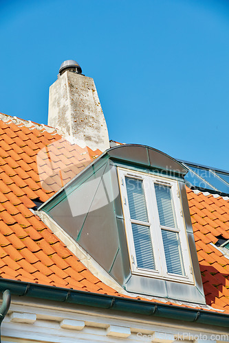 Image of Chimney chute, window and sunroof skylight designed on house building outside against blue sky background. Construction of exterior architecture on rooftop for fireplace escape and natural sunlight