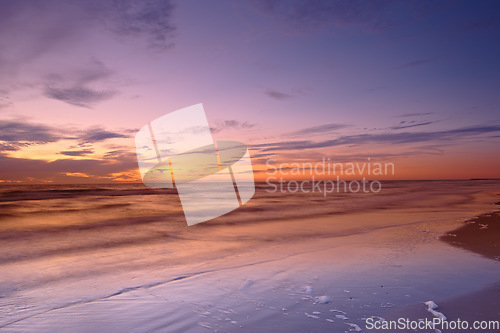 Image of Seascape and landscape of a beautiful sunset on the west coast of Jutland in Loekken, Denmark. Sun setting on the horizon on an empty beach at dusk over the ocean and sea in the evening