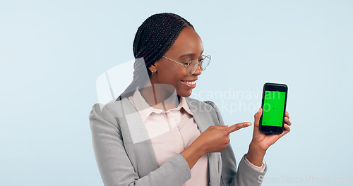 Image of Black woman, pointing at smartphone and green screen, advertising mockup with tracking marker in studio. Information, marketing for app or website, communication and ads for tech on blue background