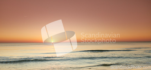 Image of Seascape and landscape of a beautiful orange sunset on the west coast of Jutland in Loekken, Denmark. Sun setting on the horizon on an empty beach at dusk over the ocean and sea at night