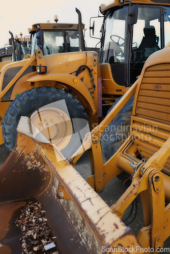 Image of Bulldozer in action at construction site. An industrial excavator on an open road section loading heavy concrete, rocks and dirt. Motorized machine equipped for pushing material, soil, sand or rubble