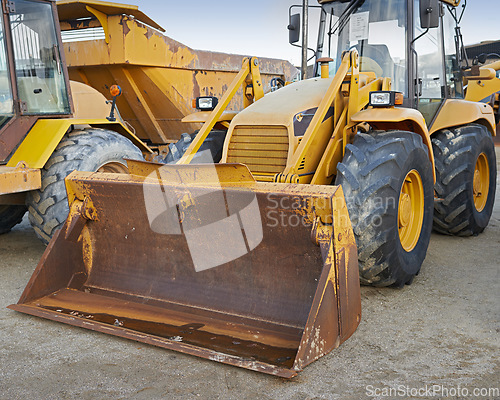 Image of Bulldozers at a construction site parked after operating. Huge orange powerful building vehicle with a hydraulic piston scoop and black wheels. Heavy machinery outside in an empty space