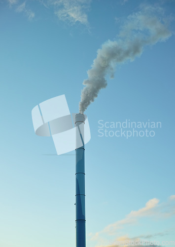 Image of A factory chimney with smoke billowing into the air. Large amounts of steam or smoke billowing from an industrial smoke stack, adding to pollution and air contamination from big industrial industries