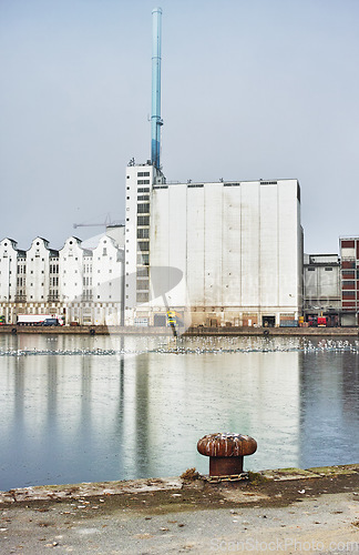 Image of A factory seen from across a body of water, industrial industry adding to air pollution, contamination and environmental pollution, deathly toxic for the planet and global state of wellbeing