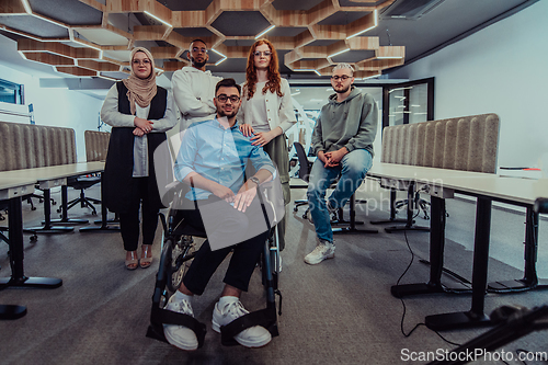 Image of Young businessmen in a modern office extend a handshake to their business colleague in a wheelchair, showcasing inclusivity, support, and unity in the corporate environment.