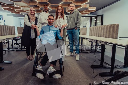 Image of Young businessmen in a modern office extend a handshake to their business colleague in a wheelchair, showcasing inclusivity, support, and unity in the corporate environment.