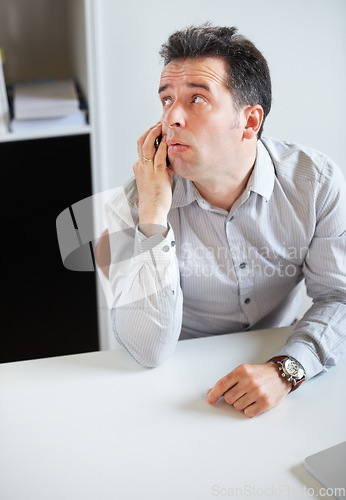 Image of Phone call, thinking or waiting with a business man sitting at his desk in the office for work. Time, contact and communication with an impatient young employee talking on his mobile in the workplace