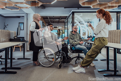 Image of Young group of business people brainstorming together in a startup space, discussing business projects, investments, and solving challenges.