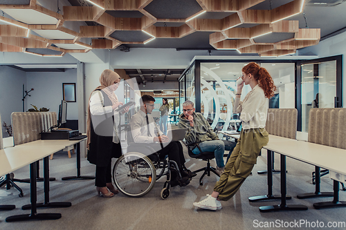 Image of Young group of business people brainstorming together in a startup space, discussing business projects, investments, and solving challenges.