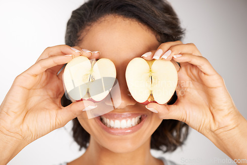 Image of Happy woman, apple and eyes for diet, nutrition or health and wellness against a gray studio background. Portrait of female person or nutritionist smile with organic fruit slices for vitamin or fiber