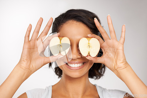 Image of Happy woman, apple and eyes for natural nutrition, diet or health and wellness against a gray studio background. Portrait of female person or nutritionist smile with organic fruit slices for vitamins