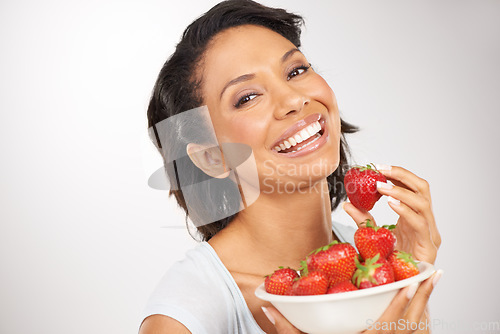 Image of Health, strawberries and young woman in a studio for wellness, nutrition and organic diet. Smile, vitamins and portrait of female person eating a fruit for healthy vegan snack by gray background.