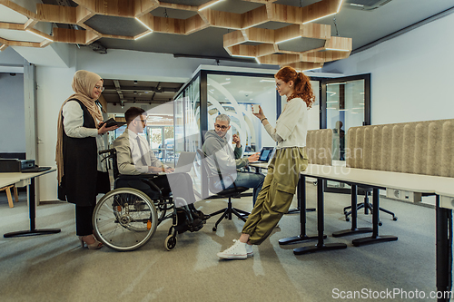 Image of Young group of business people brainstorming together in a startup space, discussing business projects, investments, and solving challenges.