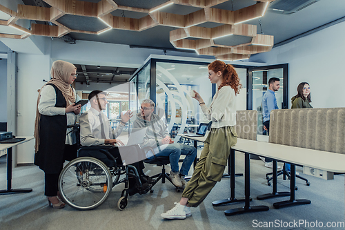 Image of Young group of business people brainstorming together in a startup space, discussing business projects, investments, and solving challenges.