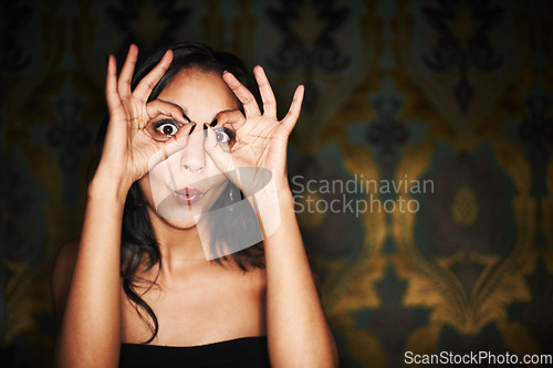 Image of Woman, hands and ok or sign on face at club, crazy and silly or goofy, energy and funny at night. Female person, dark and comedy or humor, eyes and emoji or icon, posing and agree with yes review