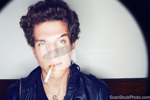 Image of Portrait of man with cigarette, punk fashion and rockstar attitude on white background with spotlight. Cool rock style, modern creative and smoking, confident face of handsome male model in studio.