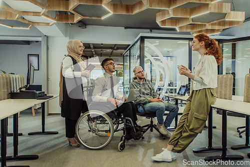 Image of Young group of business people brainstorming together in a startup space, discussing business projects, investments, and solving challenges.