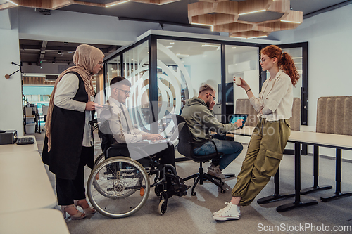 Image of Young group of business people brainstorming together in a startup space, discussing business projects, investments, and solving challenges.