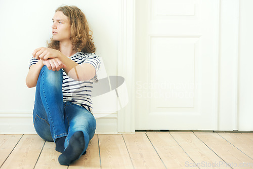 Image of Man, thinking and fashion for sitting on floor in home for looking, vision or peace. Sweden boy, male person and alone with idea for future by contemplating with curly hair, trendy or style for teen