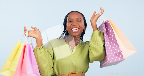 Image of Black woman, shopping bag and retail in portrait with happiness for discount on fashion giveaway in studio. Choice, happy and commerce with smile for sale, service and gift on blue background