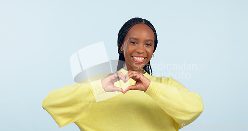 Image of Portrait, heart and hands of black woman in studio for love, kindness or charity donation on blue background. Happy model show finger sign of hope, care or thank you emoji for support, review or vote