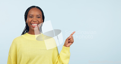Image of Pointing, smile and black woman with opportunity, portrait and announcement on a blue studio background. African person, model or girl with hand gesture, mockup space and choice with decision or news