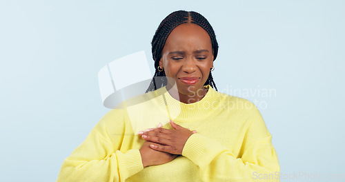 Image of Woman, sick and pain in studio for heart attack, medical crisis and cardiovascular healthcare on blue background. African model, emergency and chest with acid reflux, stroke and help for hypertension