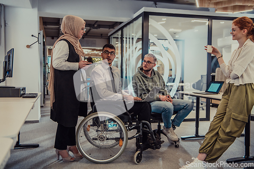 Image of Young group of business people brainstorming together in a startup space, discussing business projects, investments, and solving challenges.