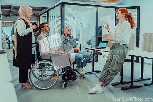 Image of Young group of business people brainstorming together in a startup space, discussing business projects, investments, and solving challenges.