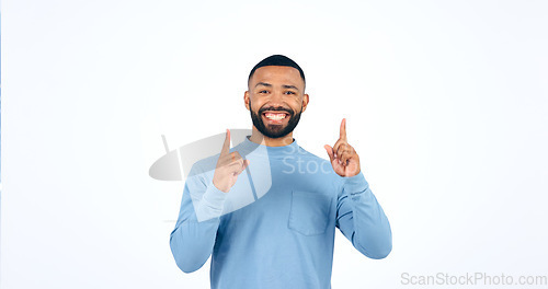 Image of Happy, face and man with hand pointing up in studio for announcement, info or promo on white background. Smile, portrait and excited male model show giveaway, deal or lottery competition prize offer