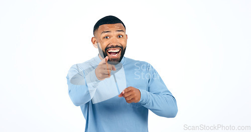 Image of Portrait, man and pointing in studio with smile for motivation, selection and encouragement on white background. Face, person and hand gesture with happiness for decision or choice with mock up space