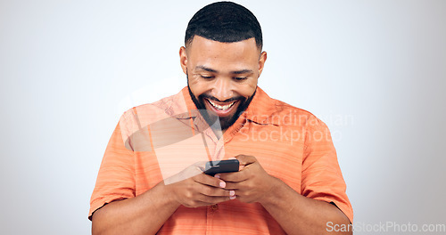 Image of Man in studio with phone, smile and typing with connection for networking, online chat or communication. Good news, notification and happy person writing message, email or post on white background.