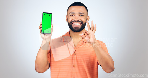 Image of Portrait, man and okay for phone with green screen, space and agreement sign in studio on white background. Happy model, smartphone and yes emoji for certified news, promotion or advertising feedback