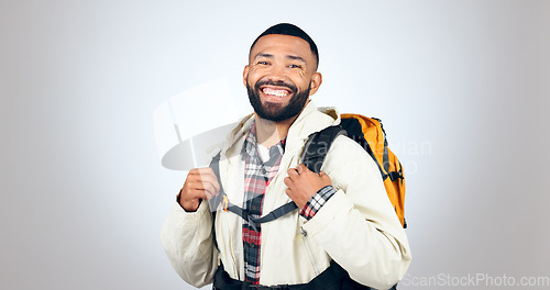 Image of Man, portrait and hiking in studio with backpack and smile from travel and freedom with adventure. Camping, fitness and grey background and walking with trekking camper gear for vacation and holiday