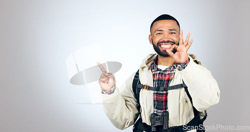 Image of Hiking portrait, pointing and happy man okay sign for studio promotion, discount deal offer or travel vacation agreement. Ok emoji icon, mockup space and studio hiker backpacking on white background