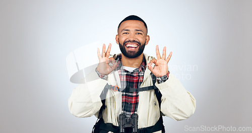 Image of Perfect sign, hiker and portrait of man in a studio with a backpack for hiking adventure. Happy, smile and young male person from Mexico with ok hand gesture for camping isolated by gray background.