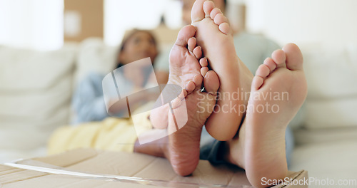 Image of Couple, feet and box for relaxing in new home for moving with investment for future, growth and love. Man, woman and together in bond, comfort or trust for real estate, property agreement or purchase