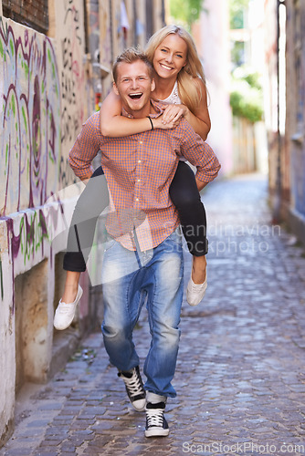 Image of Couple, happy or piggyback on street in city, fun support or romance in committed relationship. Excited man, woman and smile for adventure in amsterdam, travel and care for love together on honeymoon