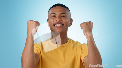 Image of Man, portrait and excited for success with fist in studio to celebrate deal, promotion or yes to winning lottery on blue background. Happy model, giveaway prize winner or reward for bonus achievement