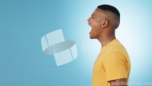 Image of Angry, man and scream in studio at mockup space for crisis, anger or mad emoji reaction on blue background. Profile of frustrated model shouting with stress, emotional conflict or negative expression
