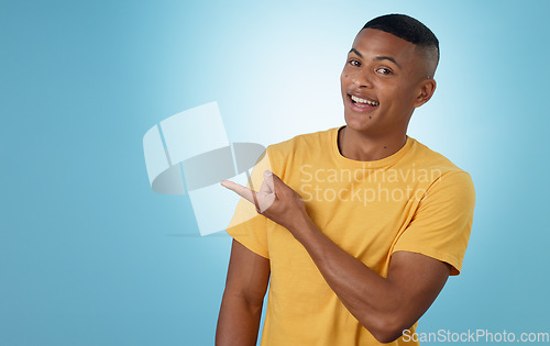 Image of Man, student pointing and presentation for education, learning or college news and information in studio. Portrait of a young person with university guide, advice and mockup on a blue background