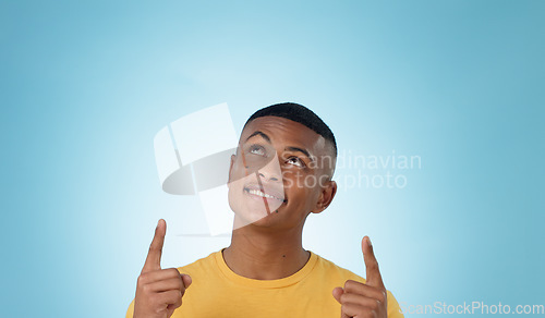 Image of Man, space and pointing up in studio for advertising choice, decision and information about us on blue background. Face, model and thinking to show presentation of mockup, promotion and announcement