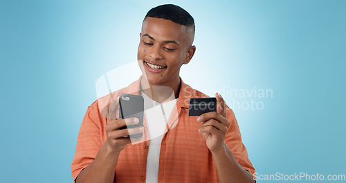 Image of Man, credit card and phone in studio, smile on face, sale and discount with fintech by blue background. Person, smartphone and online shopping with e commerce, easy payment and happy with banking app