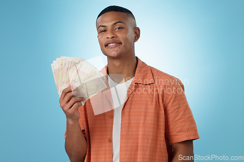 Image of Young man, winner and money fan with success, bonus or winning in competition, college loan or cashback in studio. Portrait of student with cash, savings and scholarship funding on a blue background