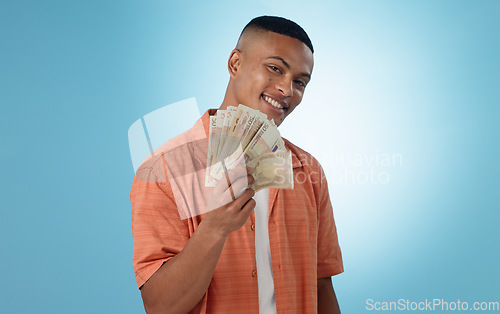 Image of Happy man, winner and money fan with success, bonus or winning in competition, college loan or cashback in studio. Portrait of student with cash, savings and scholarship funding on a blue background