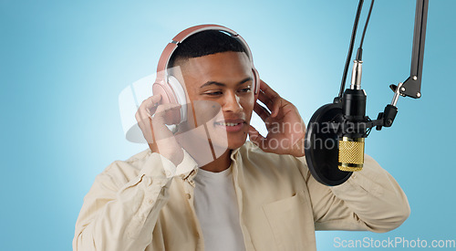 Image of Artist man, headphones and mic in studio with thinking, ideas and creativity for song by blue background. Musician, person and microphone with recording, production and performance with singing voice