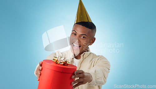 Image of Happy man, party hat and gift for celebration in studio, blue background and portrait for mock up in Cape Town. Male model, present and bow for birthday, giveaway or event for reward, bonus or prize